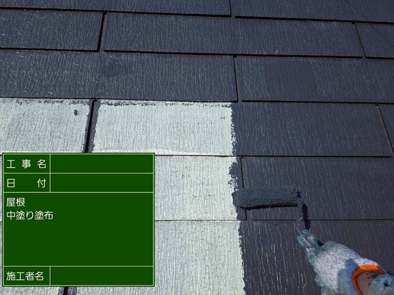 白い屋根に黒色の中塗り材を塗装中